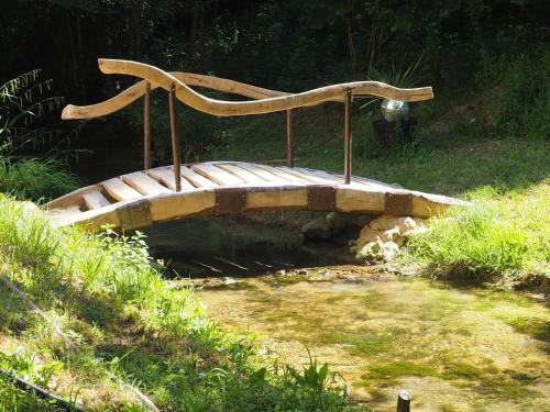 un banc en bois assis sur un pont dans un champ dans l'établissement Moulin Bas, Prés de la Rivière, à Carnac-Rouffiac