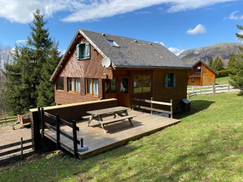 une terrasse en bois avec une table de pique-nique devant une cabine dans l'établissement Appartement - Chalet MONT DORE COSY 6/7 personnes, à Le Mont-Dore