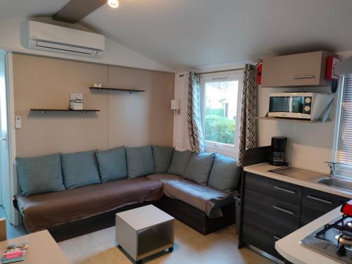 a living room with a couch and a kitchen at Mobil home Menanteau in Les Mathes