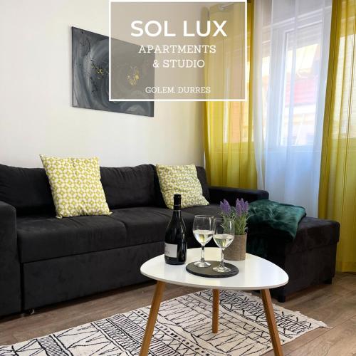 sala de estar con sofá negro y mesa con copas de vino en SOL Lux Apartments 1st Floor, en Durrës