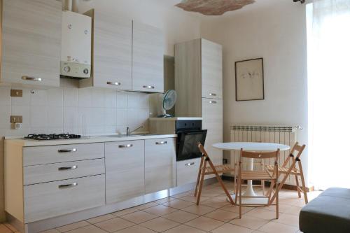 a kitchen with white cabinets and a table with chairs at Le Residenze Della Poetessa in Corsico