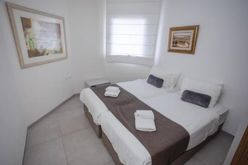 a white room with a bed with two towels on it at Luxury apartments Boutique Haneviim in Jerusalem