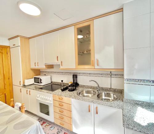een keuken met een wastafel en een magnetron bij Apartamento Bellavista in Portonovo