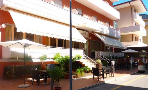 カットーリカにあるHOTEL D'ANNUNZIOのテーブル・椅子・傘付きの建物