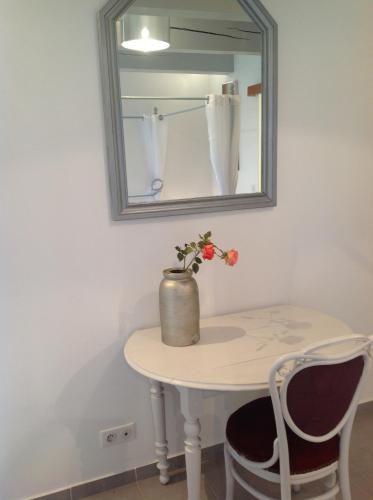 a table with a mirror and a vase with flowers on it at Bastide de l'Ovalie in Bagnols-en-Forêt