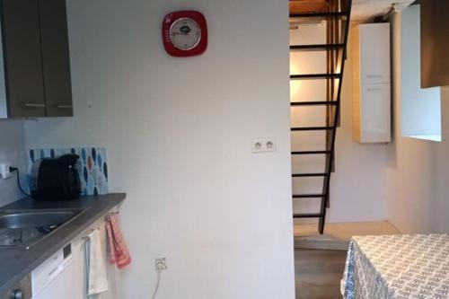 una cocina con fregadero y un reloj en la pared en Chalet climatisé en bordure de rivière mansardée, en Trébas