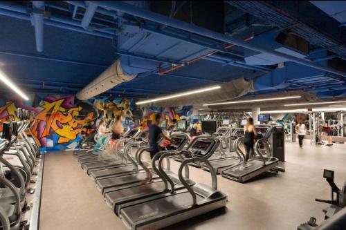 a gym with rows of treadmills and a wall of graffiti at Orchid Hotel Beachfront 2BR Apartment in Tel Aviv