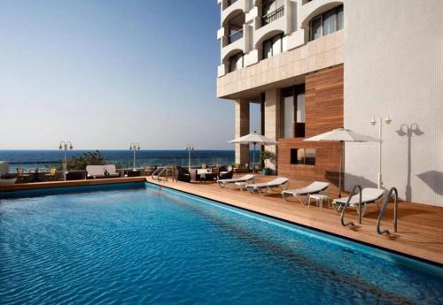 a swimming pool in front of a building at Orchid Hotel Beachfront 2BR Apartment in Tel Aviv