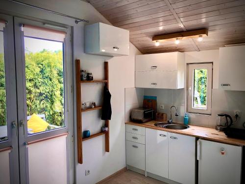 Elle comprend une petite cuisine avec des placards blancs et une fenêtre. dans l'établissement Domki pod gwieździstym niebem, à Zastań