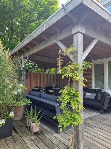 a pergola with blue couches on a wooden deck at Het Pauwtje in Zoutelande