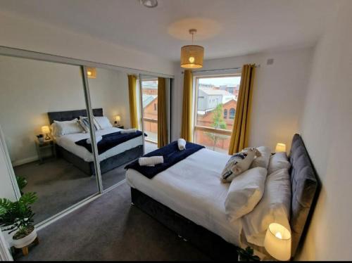 a bedroom with two beds and a large window at Modern apartment, sleeps 6, Belfast city centre in Belfast