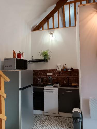 a kitchen with white appliances and a brick wall at L'écurie in Méneslies