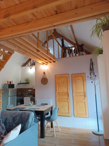 a living room with wooden ceilings and a table and chairs at L'écurie in Méneslies