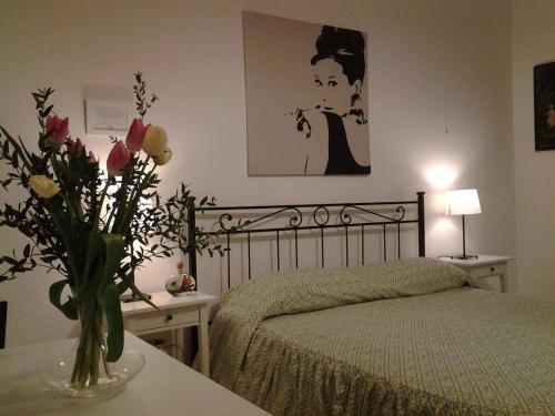 ローマにあるB&B Trastevere in Bedのベッドルーム1室(ベッド1台、テーブルの上に花瓶1枚付)