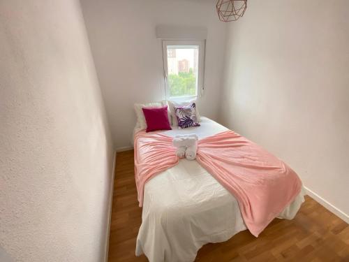 ein kleines Schlafzimmer mit einem rosa und weißen Bett und einem Fenster in der Unterkunft Gran Piso Retiro Corregidor in Madrid
