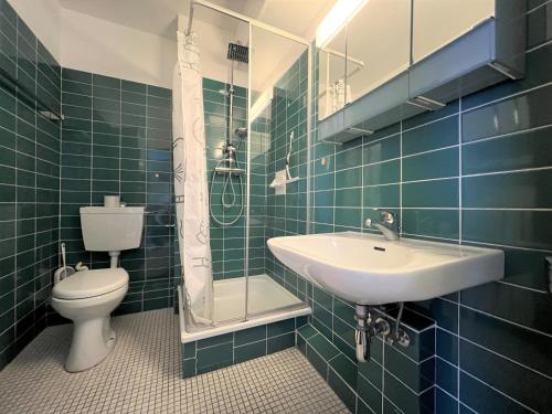 ein grün gefliestes Bad mit einem Waschbecken und einem WC in der Unterkunft Ferienpark Sierksdorf App 580 - Strandlage in Sierksdorf