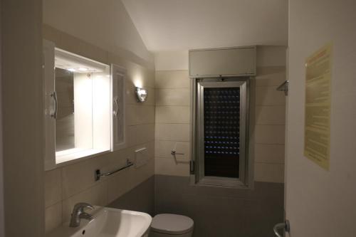 a bathroom with a sink and a toilet and a window at Quadrifoglio 43 in Bibione