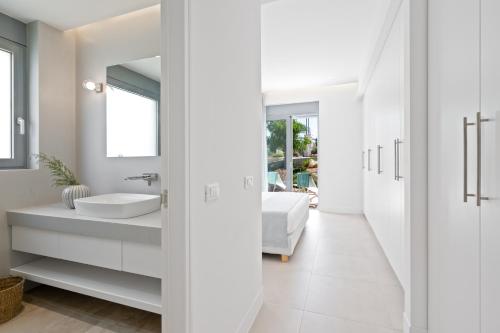 W białej łazience znajduje się umywalka i lustro. w obiekcie Le Mont Blanc w mieście Kounoupidiana