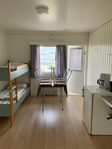 a room with two bunk beds and a table and a window at Solvang Ferietun in Vangsnes