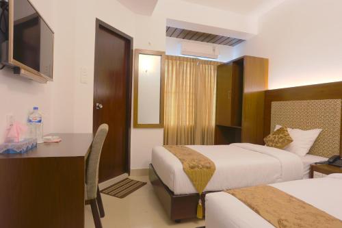 a hotel room with two beds and a desk at Holy Inn Sylhet in Sylhet