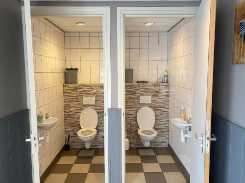 a bathroom with two toilets and two sinks at Camping De Nieuwe Hof in Otterlo