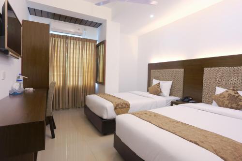 a hotel room with two beds and a desk at Holy Inn Sylhet in Sylhet
