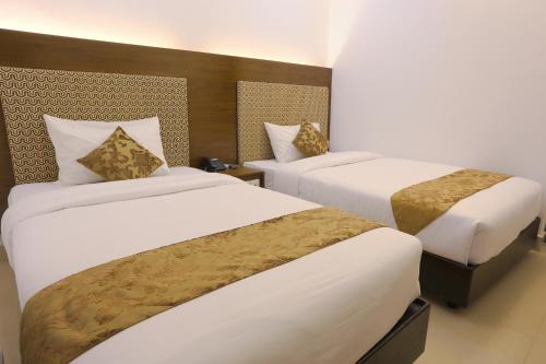 a hotel room with two beds with white sheets at Holy Inn Sylhet in Sylhet