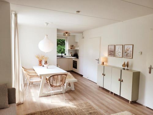 uma cozinha e sala de jantar com uma mesa branca e cadeiras em Scandinavian Wellness met hottub & sauna em Ewijk