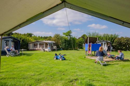 eine Gruppe von Menschen, die im Gras unter einem Zelt sitzen in der Unterkunft De Veenborg in Kolham
