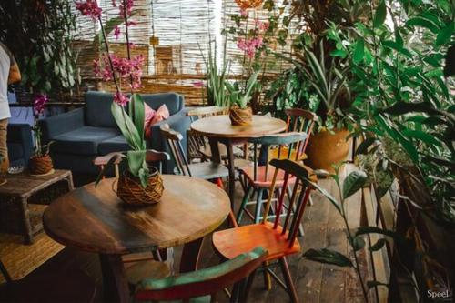 a patio with tables and chairs and potted plants at Happy Paradise Hostel in Natal