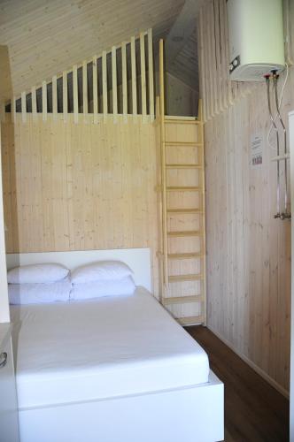 Schlafzimmer mit einem weißen Bett und Holzwänden in der Unterkunft Namelis Genio 7 in Palanga