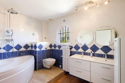 La salle de bains bleue et blanche est pourvue d'une baignoire et de toilettes. dans l'établissement Superbe Villa Provençale - Piscine - 3 chambres, à Montauroux