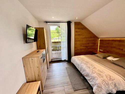 1 dormitorio con 1 cama y TV en la pared en Apartmány na Horce en Blata