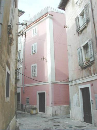 a pink building in an alley between two buildings at Tartini - private roof terrace - self check-in in Piran