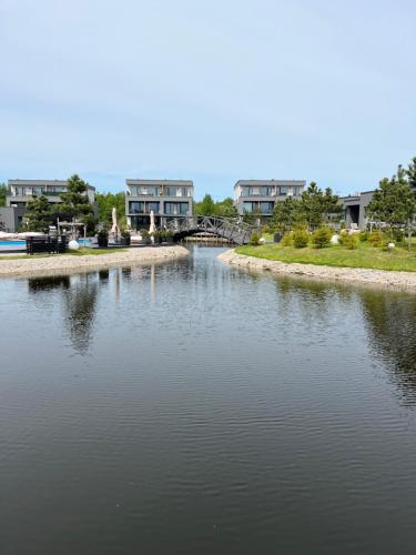 a body of water with houses in the background at PUŠIS IR JŪRA - Mano Jūra 2 complex - Kunigiškiai in Palanga