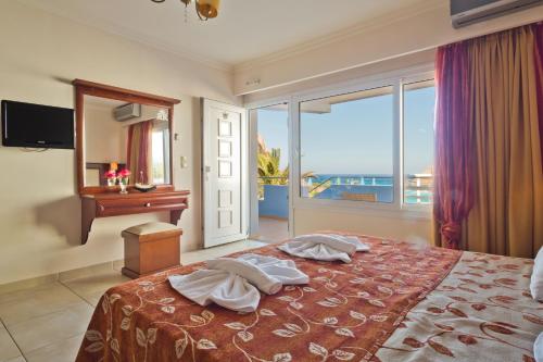 a bedroom with a bed with a view of the ocean at Royal Beach Hotel in Arkasa