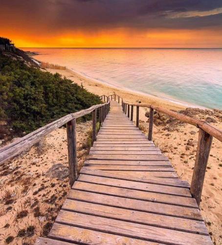 a wooden pathway to the beach at sunset at B&B Sole Mare Vento in Maruggio