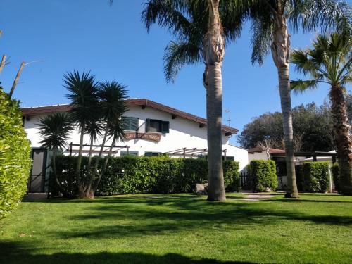 a white house with palm trees in the yard at Agriturismo Fratelli Mizzon in Sabaudia