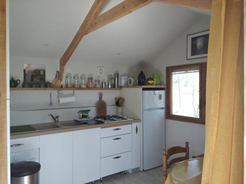 a kitchen with white cabinets and a white refrigerator at Cabane sous les Chênes in Montagnac