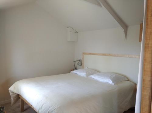 1 dormitorio con 1 cama blanca y 2 almohadas en Cabane sous les Chênes, en Montagnac