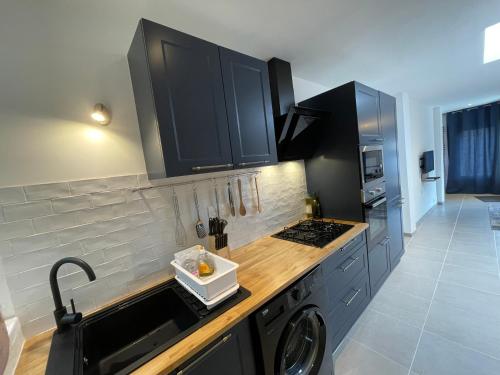 une cuisine avec des armoires noires et un lave-linge dans l'établissement Appartement Étables-Sur-Mer à 10 minutes à pied de la mer, en plein centre-ville, à Étables
