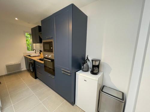 La cuisine est équipée de placards bleus et d'un réfrigérateur blanc. dans l'établissement Appartement Étables-Sur-Mer à 10 minutes à pied de la mer, en plein centre-ville, à Étables