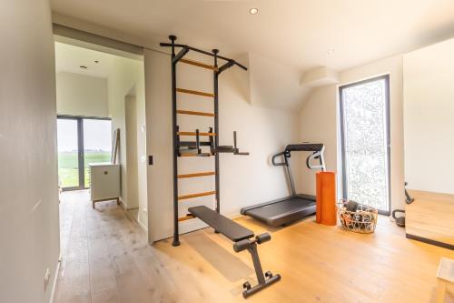a gym with a treadmill and a exercise bike in a room at Villa Polderzicht, private luxurious stunning views in Cadzand