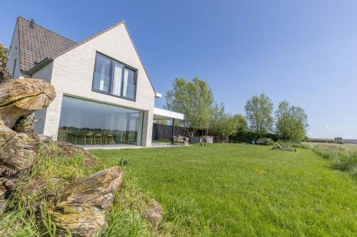 a house on a grassy field with a building at Villa Polderzicht, private luxurious stunning views in Cadzand