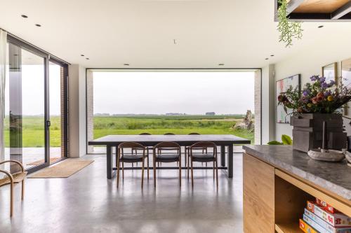 a dining room with a table and chairs and a large window at Villa Polderzicht, private luxurious stunning views in Cadzand