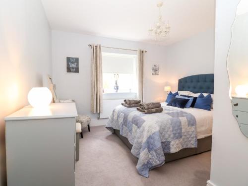 a white bedroom with a bed and a window at East View in Cheltenham