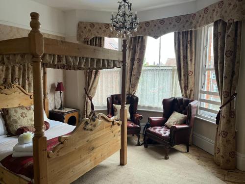 a bedroom with a canopy bed and two chairs at Baytree House in Lowestoft