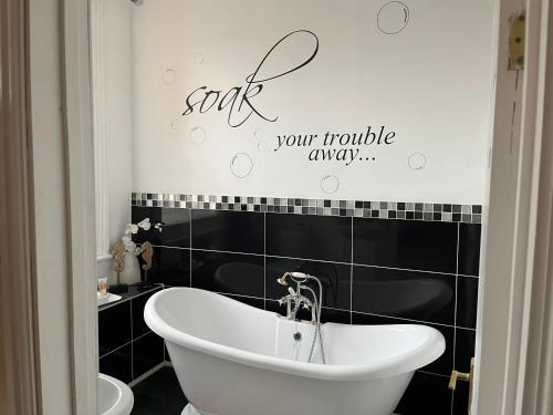 a bathroom with a bathtub and a sign on the wall at Baytree House in Lowestoft