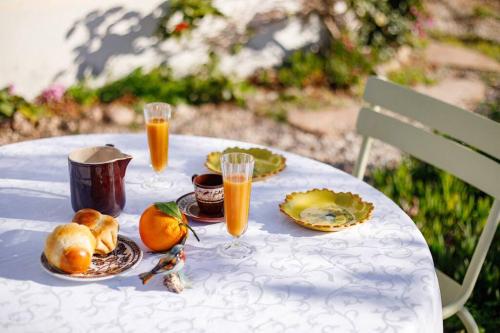 einen Tisch mit Obstteller und Gläsern Orangensaft in der Unterkunft Studio les pieds dans l'eau et immense jardin in Carqueiranne