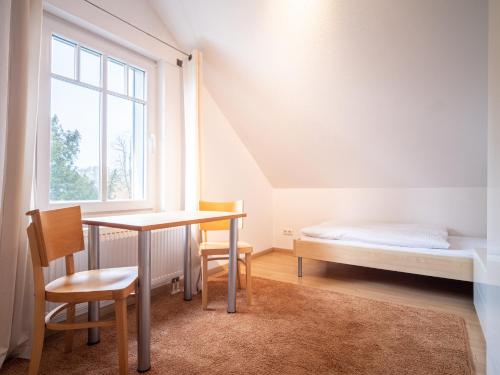 een slaapkamer met een tafel, een bed en een raam bij Grüne Straße FeWo G4 (DG rechts) in Prerow